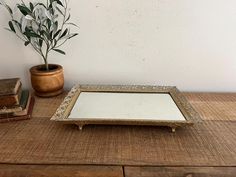 a small mirror sitting on top of a wooden table next to a potted plant