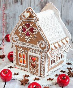 a gingerbread house with hearts on the roof and decorations around it, sitting on a wooden table