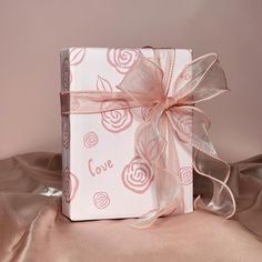 a white box with pink roses on it and a ribbon tied around the lid that says love