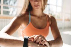 a woman in an orange tank top is holding onto her wrist with the other hand