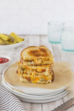 a grilled cheese sandwich sitting on top of a white plate next to a bowl of pickles