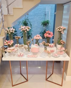 a table topped with lots of pink flowers and cake next to a stair case filled with potted plants