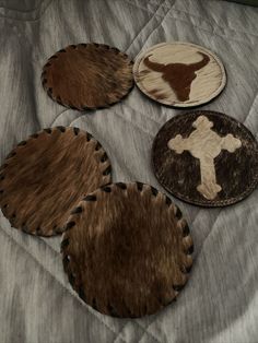 four cow hide coasters on a bed