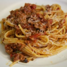 spaghetti with meat sauce and parmesan cheese on white plate