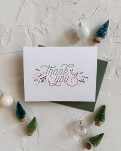 a thank you card sitting on top of a table next to christmas decorations and ornaments