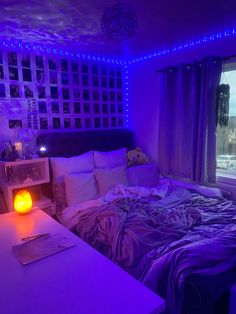 a bedroom with purple lights and a bed in the corner, next to a window