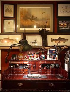 an old fashioned desk with various items on it and framed pictures above the top shelf