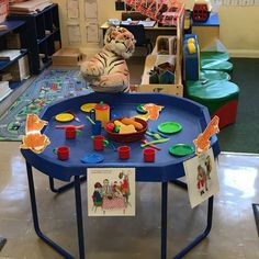 a tiger sitting at a table in a classroom with pictures and cards on the table