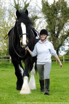 a woman leading a black and white horse