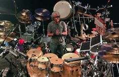 a man standing in front of a bunch of drums on top of a drum set