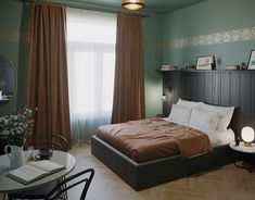 a bed sitting in a bedroom next to a table with a lamp on top of it