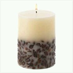 a lit candle with coffee beans on it