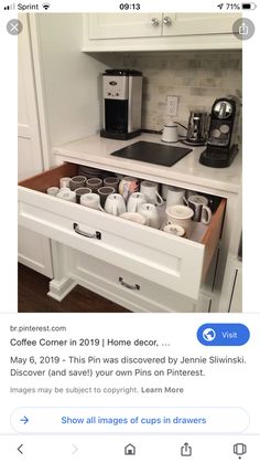 an open drawer in the middle of a kitchen with coffee pots and cups on it