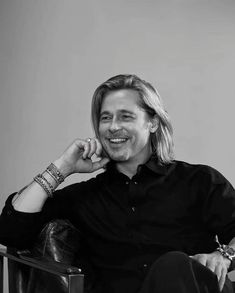 a black and white photo of a man sitting in a chair with his hand on his chin