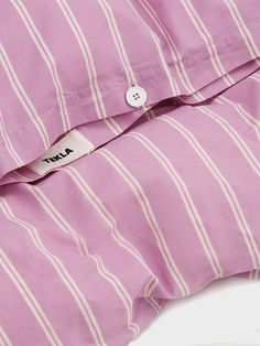 a pink and white striped shirt with a tag on it's collar, sitting on top of a bed