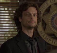 a man in a suit and tie standing next to a police badge