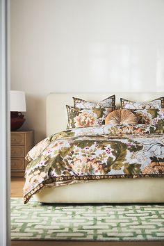 a bed with floral comforter and pillows in a room