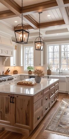 a large kitchen with an island in the middle and two hanging lights above it on the ceiling