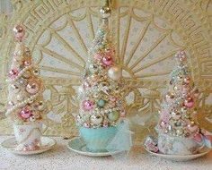 three small christmas trees sitting on top of a table next to plates and saucers