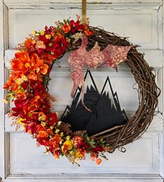 a wreath with an image of a horse and mountains is hanging on the front door