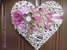 a heart shaped decoration hanging on a door with pink and white flowers in the center