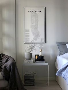 a bedroom with a bed, nightstand and pictures on the wall above it that says new york