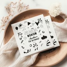 two greeting cards with panda designs on them sitting on a plate next to some dried flowers