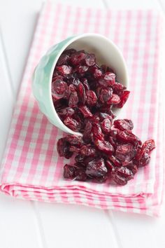 cranberries in a small bowl on a pink and white checkered napkin next to a spoon