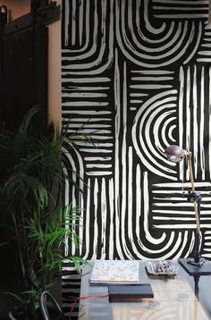 a table with a lamp and some plants on it in front of a black and white wall