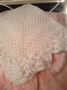 a white crocheted blanket laying on top of a bed