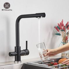 a woman is filling a glass with water from the faucet