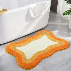 an orange and white bath mat sitting on the floor in front of a bath tub