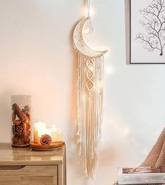 a white wall hanging with a crescent moon and some candles on the table next to it