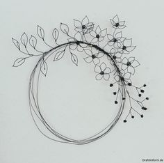 a wire wreath with black beads and flowers on white paper, in the shape of a circle