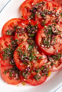 a white plate topped with sliced tomatoes and herbs