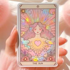 the sun tarot card is being held by someone's hand with pink flowers