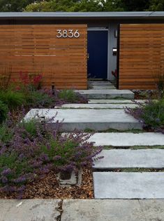 a house with steps leading up to the front door and purple flowers growing on the side