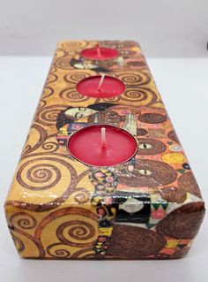 two red candles are sitting in a decorative box