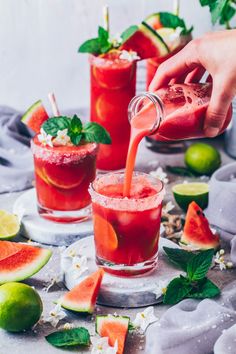 a person pouring watermelon juice into two glasses with slices of watermelon and mint on the side