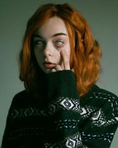 a woman with red hair wearing a sweater