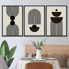 three black and white art pieces hanging on the wall above a table with a vase