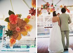 the bride and groom are standing under an umbrella with paper flowers hanging from it's side