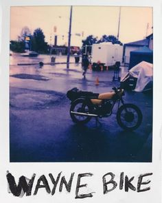 an old photo of a motorcycle parked on the side of the road in the rain