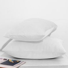 two white pillows sitting next to each other on top of a wooden table in front of a magazine