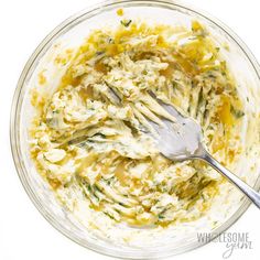 a glass bowl filled with food and a silver fork in it on top of a white table