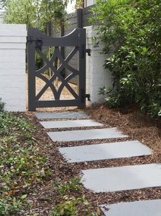 a white house with a black gate in the front yard and landscaping around it,