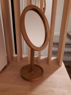 a wooden stand with an oval mirror on it's top, and some stairs in the background