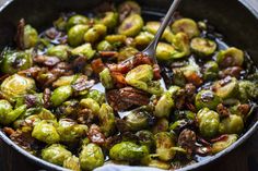 the brussel sprouts are being cooked in a skillet with a spoon