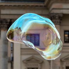 a close up of a glass object in front of a building with columns and windows