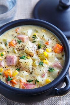 a bowl of soup with ham, potatoes and carrots